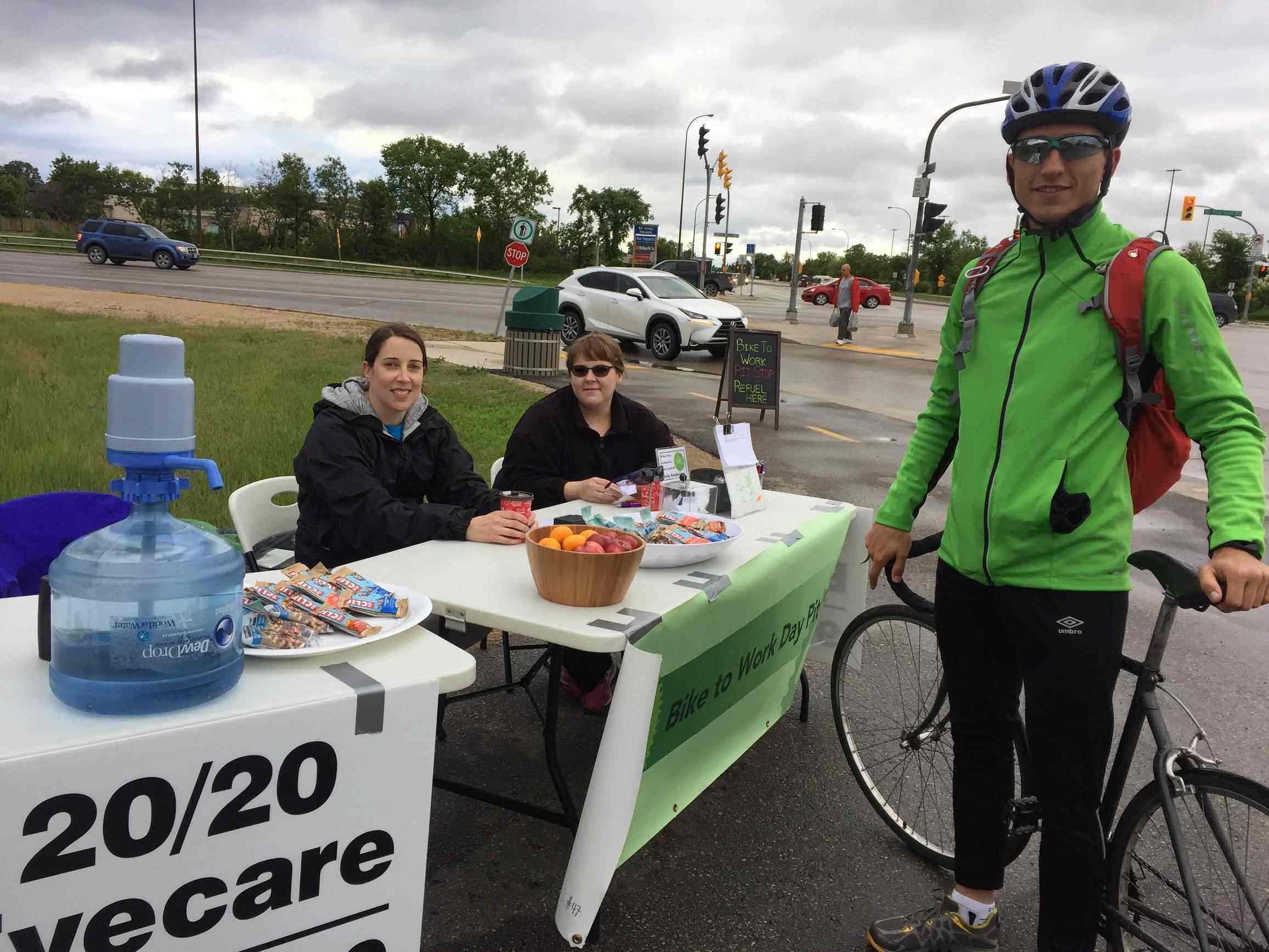 Pit Stop set up 20/20 Staff posing with cyclist at pit stop table